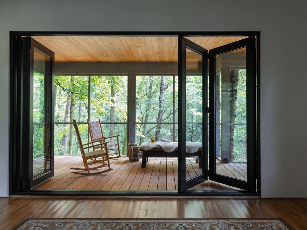 Marvin Ultimate Wood-clad bi-fold patio doors open treetop view in a mountain home