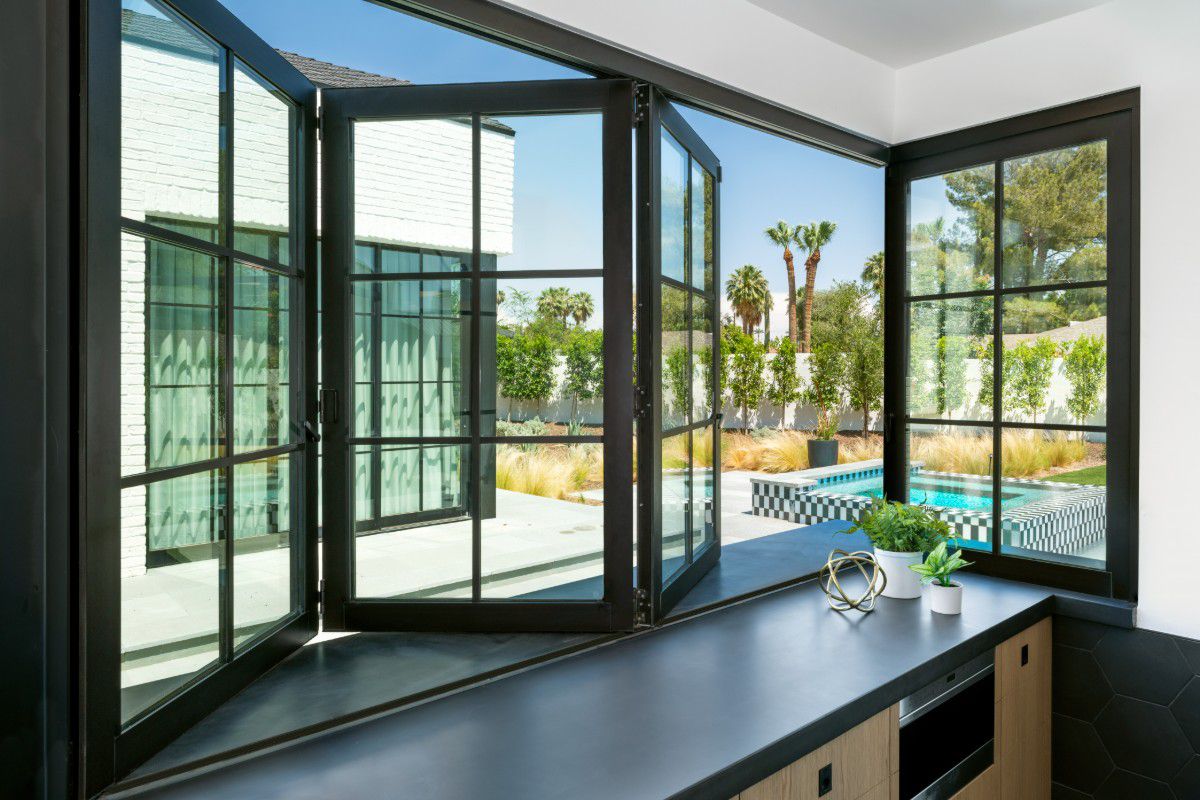 Western Architectural Openings folding windows connect the kitchen to an outdoor counter for casual dining.