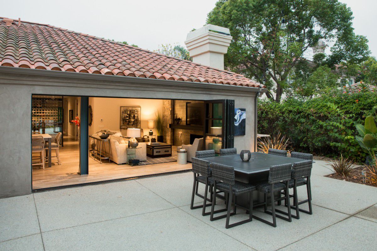 Western Architectural Openings bronze anodized folding patio doors create a wide opening for seamless indoor-outdoor dining.