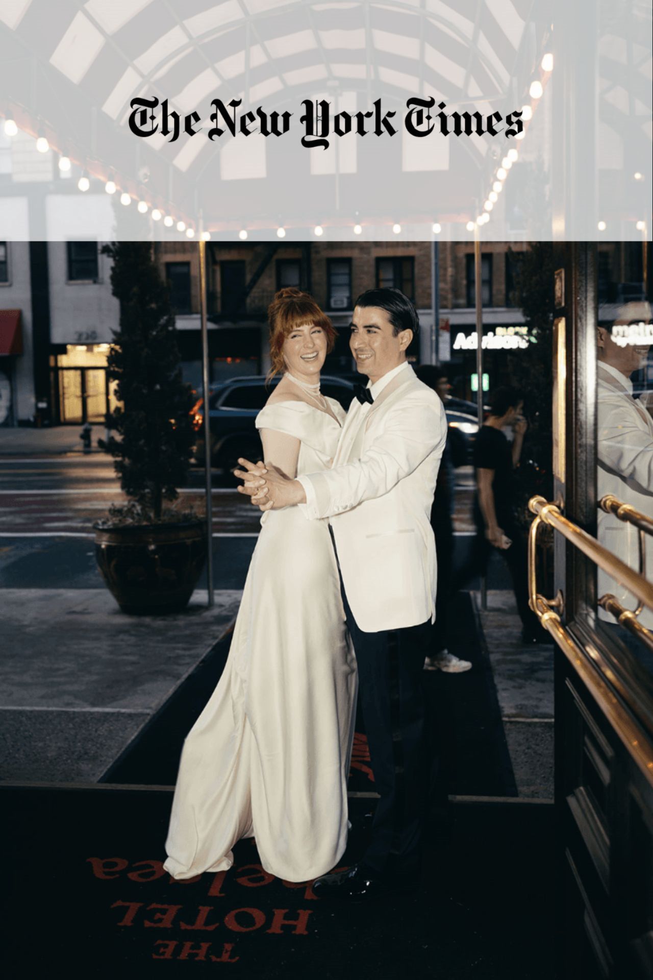 Bride and groom standing in front of a hotel with city street and traffic in the background.