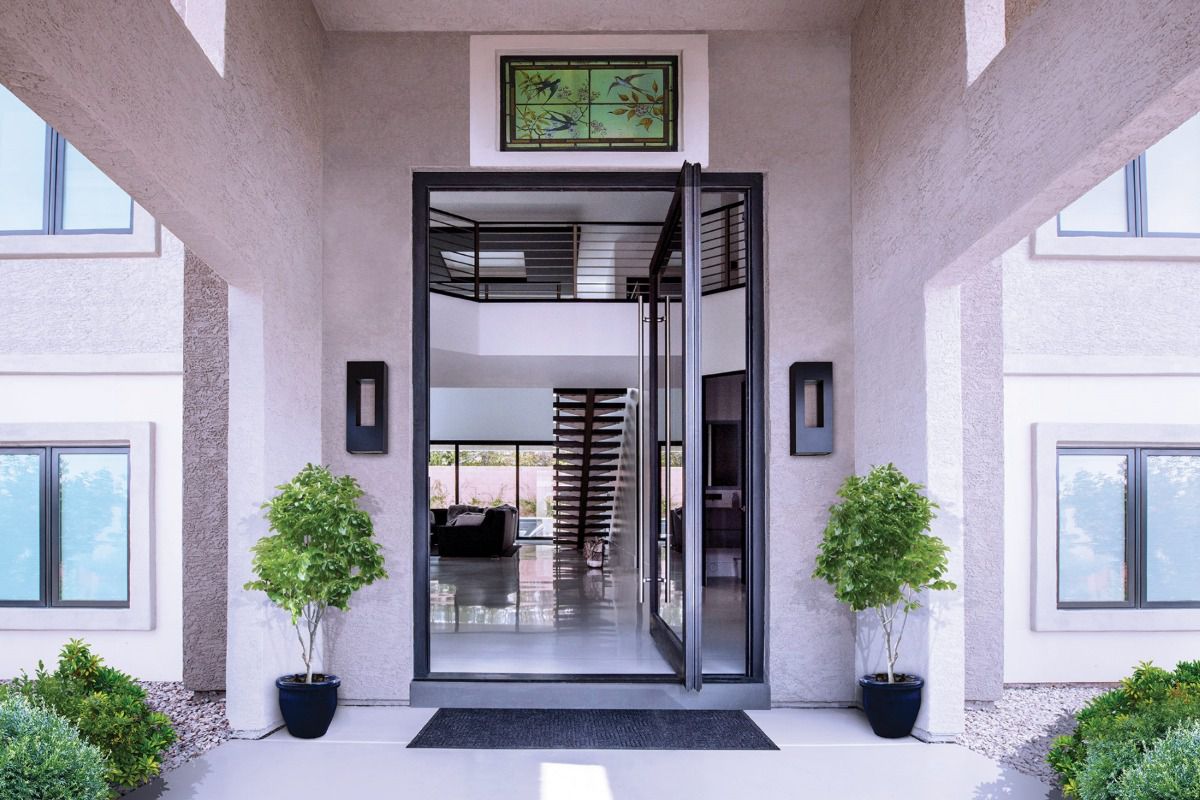 All Weather Series 7200 aluminum pivot entry door with glass panels creates a dramatic entrance to a contemporary home.
