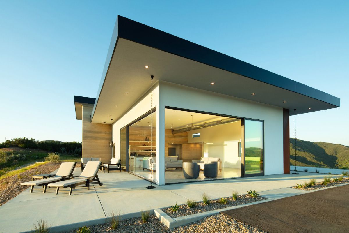 All Weather Series 8100 aluminum multi-slide doors open at the corner, connecting a modern home's living space to an outdoor terrace.