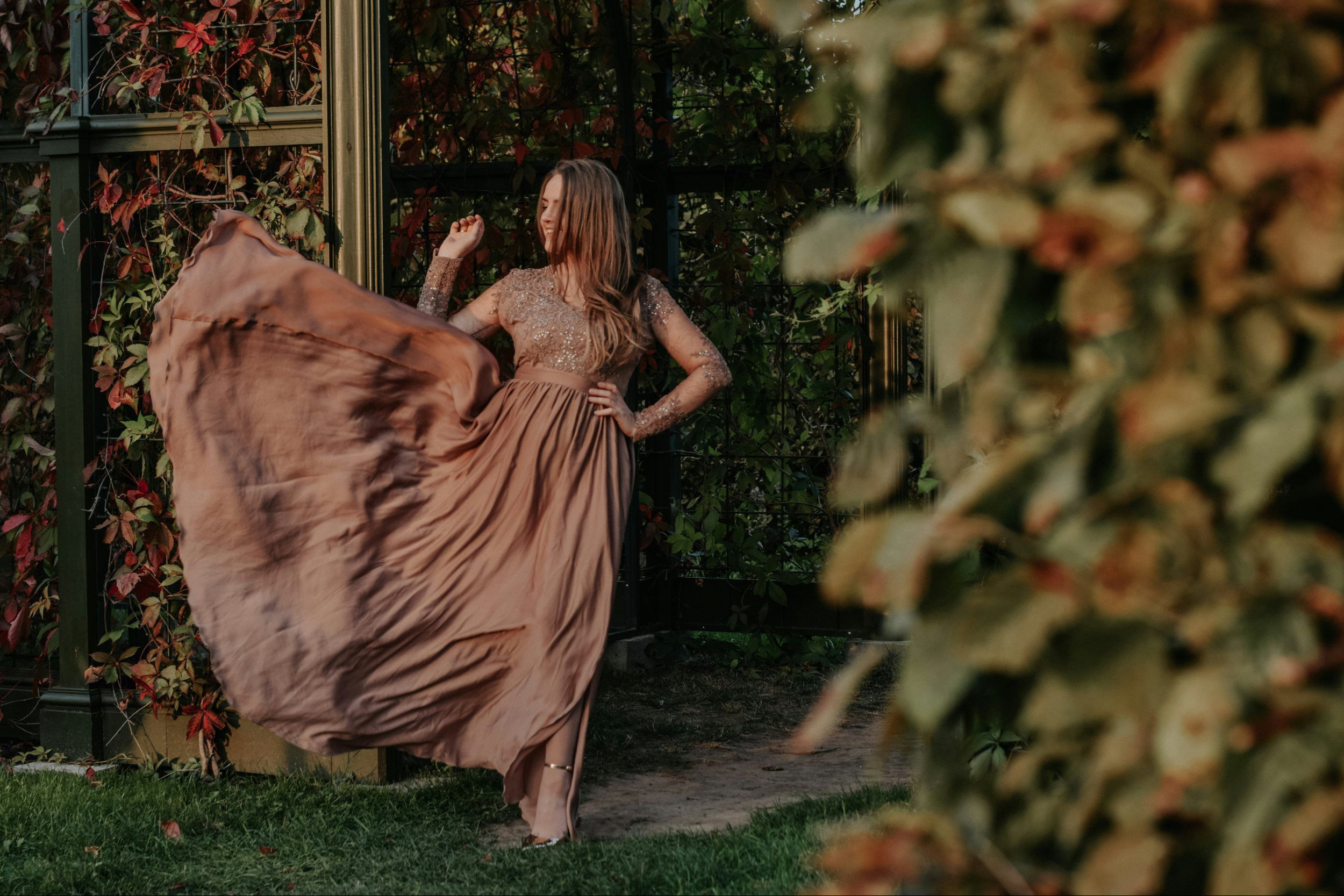 A lace dress hanging on a terracotta wall with ivy showcasing the versatility of wedding dresses that can be used for multiple occasions by Weddings & Events by K’Mich.