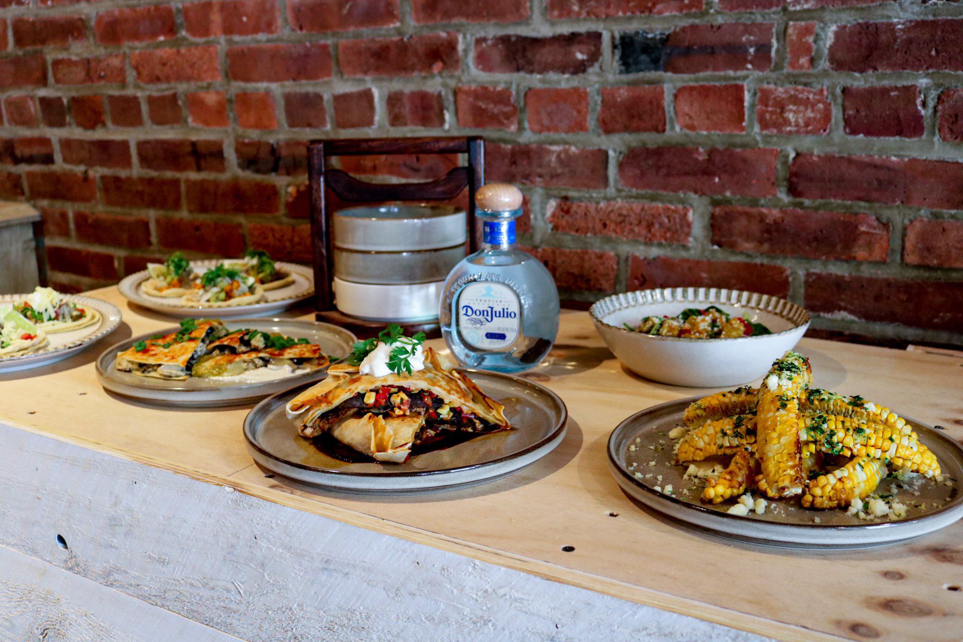 Spread of Street Corn ‘Ribs’, Spinach Salad, Quesadilla, Tacos, Blue Corn Crunch Wrap, Don Julio Tequila Bottle