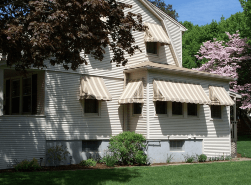 These beige striped awnings blend with the colonial architecture to create a uniform and appealing facade. Mineola Signs provides shade solutions that fit seamlessly with residential aesthetics throughout the tri-state area.