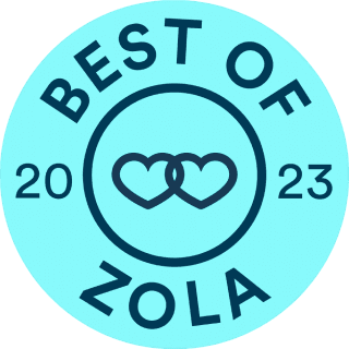 A blue circular badge featuring the text "Best of Zola 2023" with two interlocking heart outlines at its center, capturing the spirit of Weddings by K'Mich wedding planners in Philadelphia