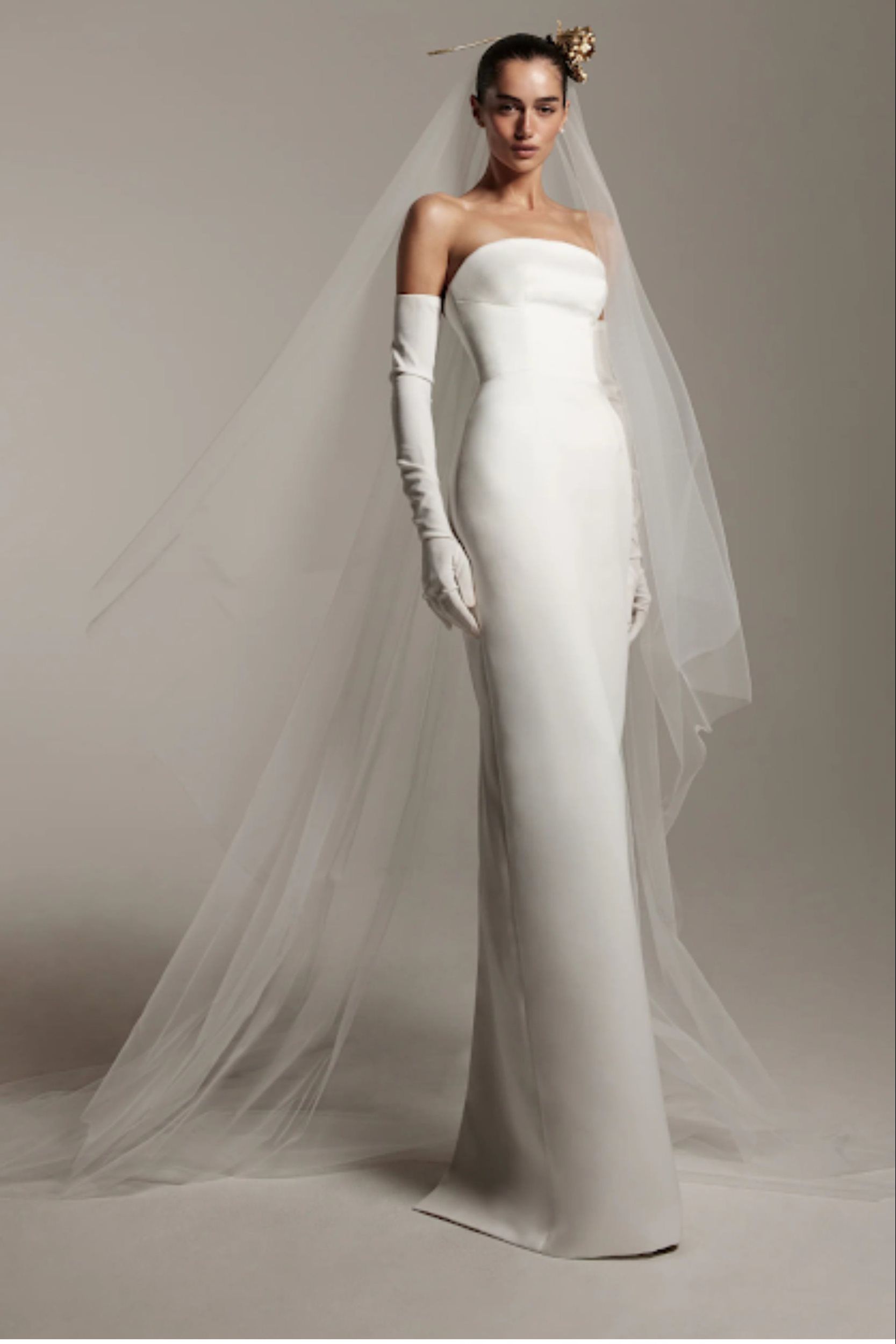 Monique Lhuillier 2026 bridal gown featuring modern minimalist design with long gloves and dramatic veil