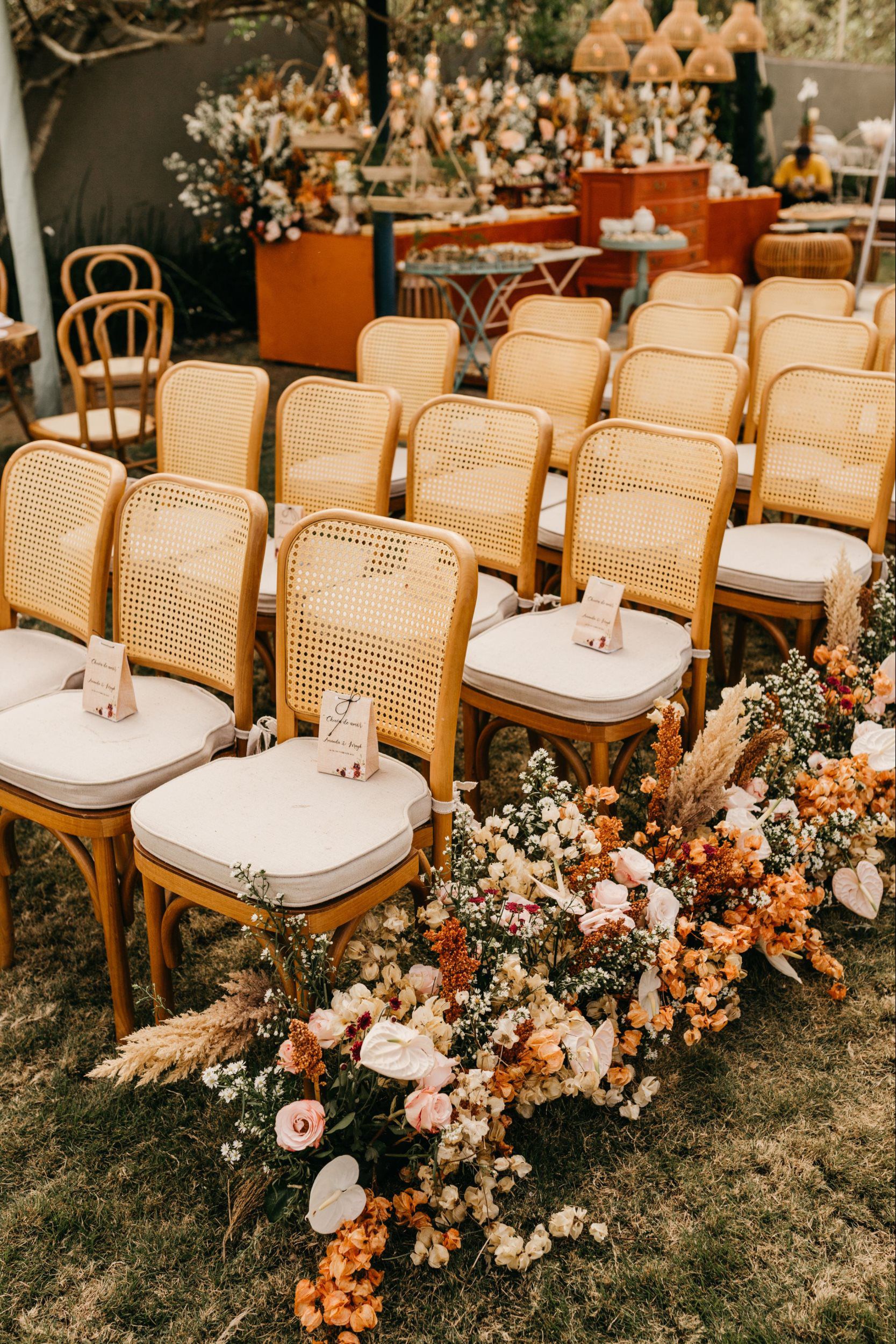 Summer wedding ceremony setup with rattan chairs and vibrant floral aisle arrangements for an outdoor celebration