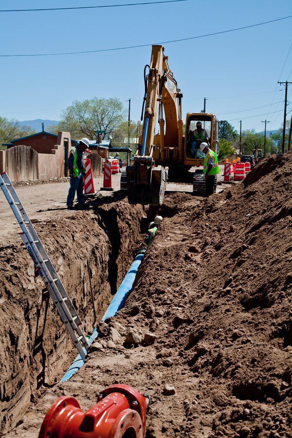 Excavator digging trench for utility pipes
