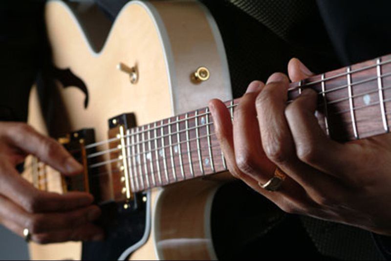person with fingers on the guitar