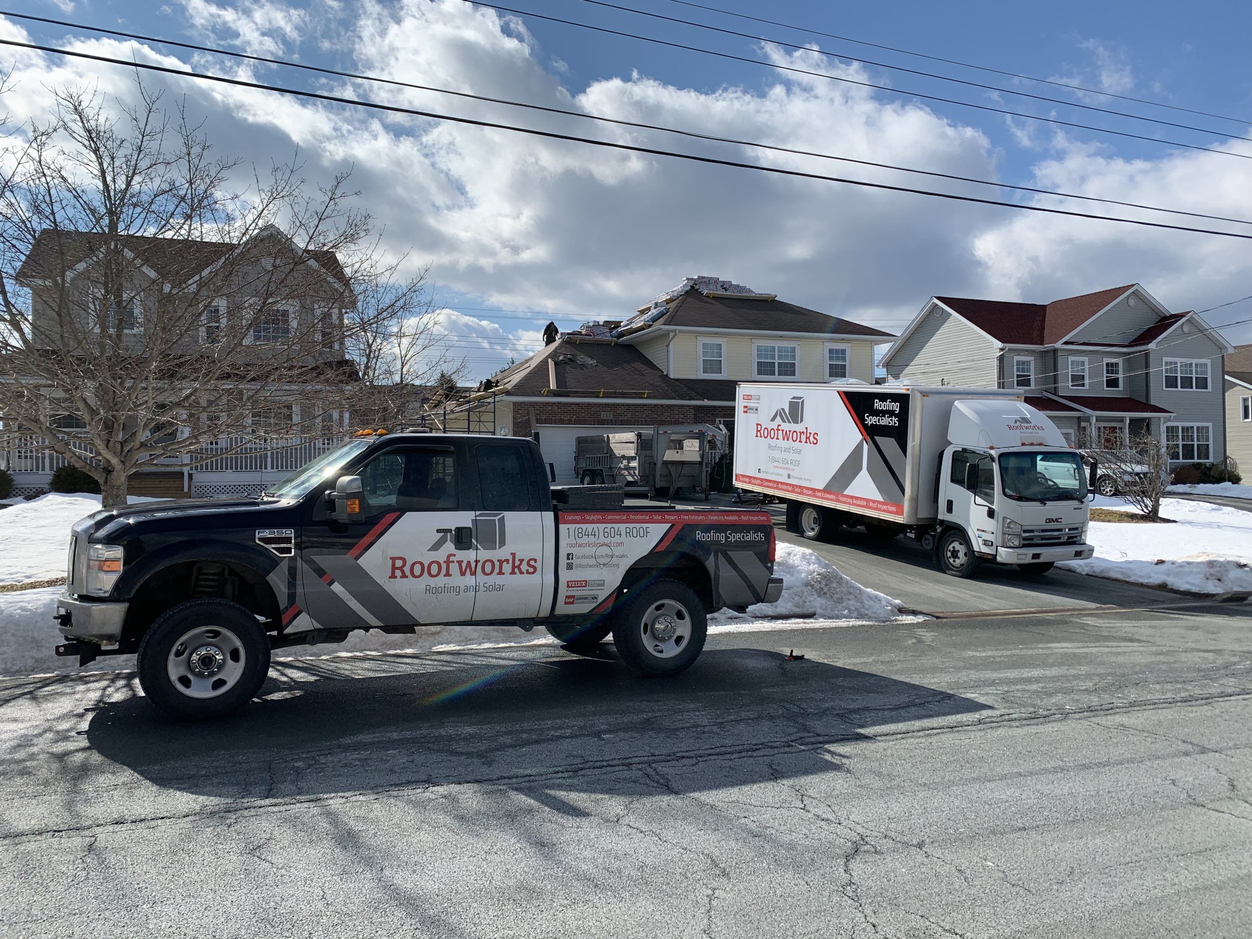 Two Roofworks work truck parked in front of house during winter roof install