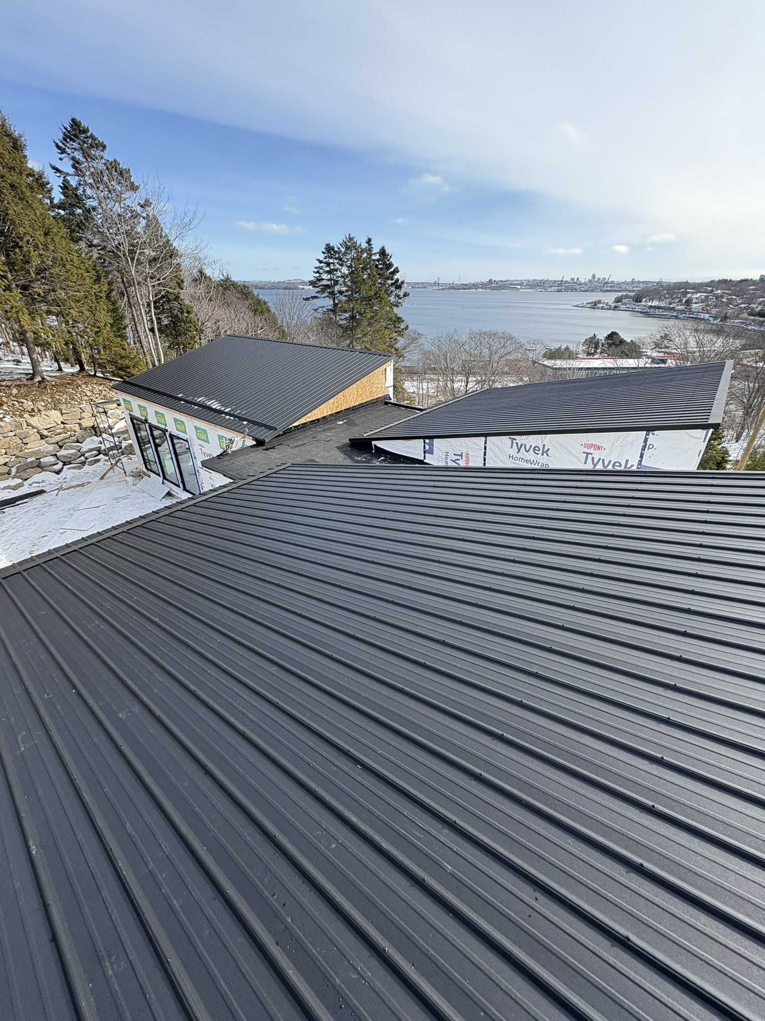 Expanded view of rooftop with black metal roof and flat roof breezeway