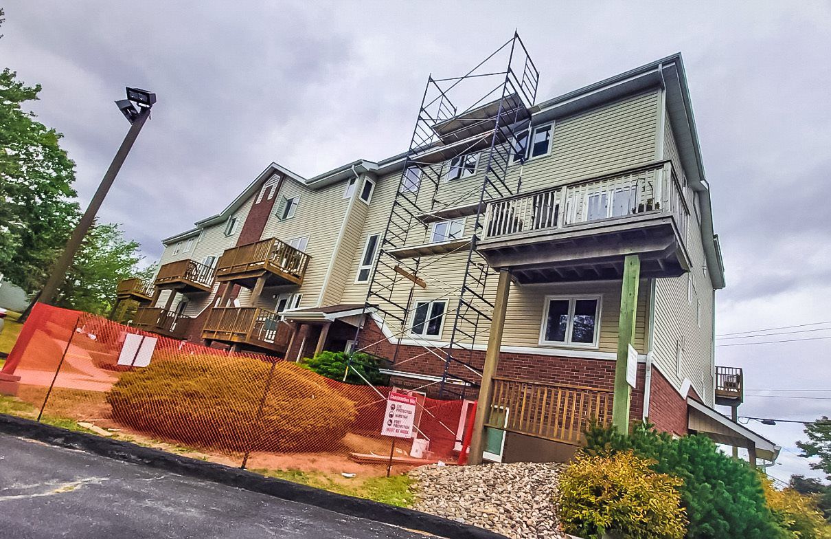 Large Multi Unit Condo building with scaffold set up during roof installation.