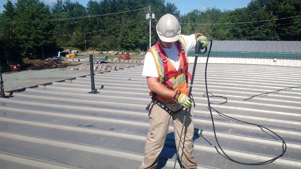 Man power washing commercial metal roof before making repairs