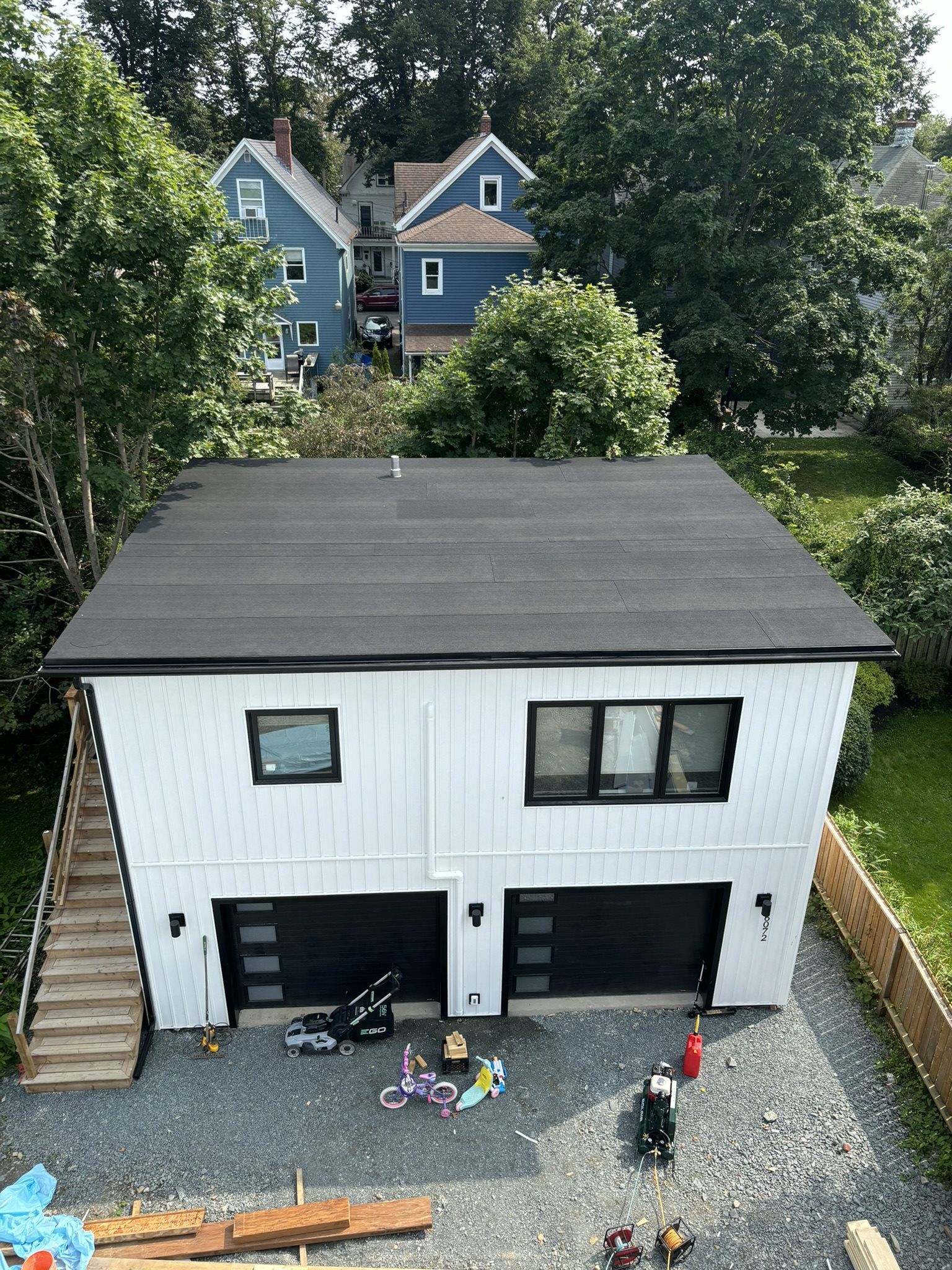 Modern Tiny home with roof, white siding and black roof by Soprema and Roofworks