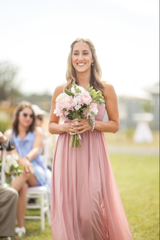 maid of honor walking with bouquet of flowers