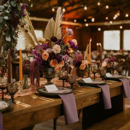 Rustic chic wedding reception table setting with deep purple and blush florals, pampas grass centerpiece, and gold flatware in Pennsylvania barn venue by Weddings & Events By K'Mich