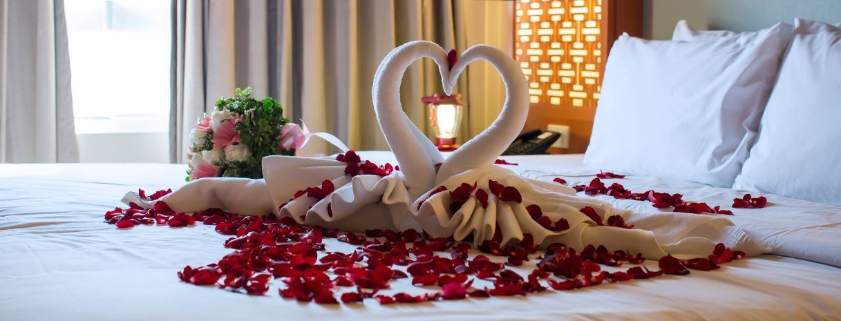 Romantic Philadelphia mini-moon hotel setup featuring towel swans, rose petals, and floral accents. Inspiration for a post-wedding getaway close to home - Weddings & Events by K’Mich 