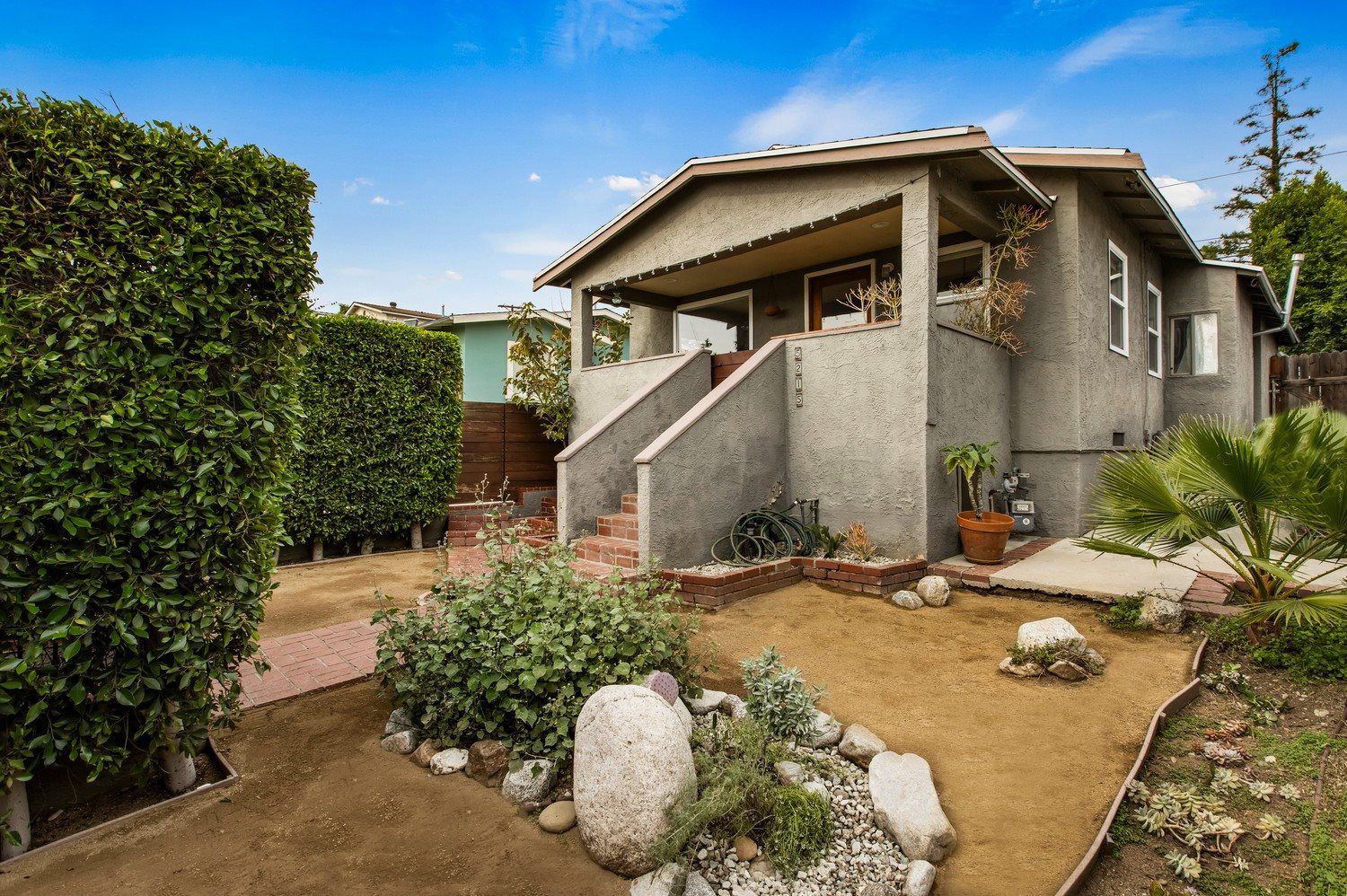 Charming Los Angeles home in the 90042 neighborhood featuring gray stucco exterior, front porch, brick walkway, and native landscaping.