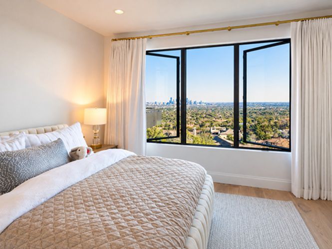 Modern bedroom featuring black-framed replacement windows in Roseville, CA, overlooking a scenic landscape.